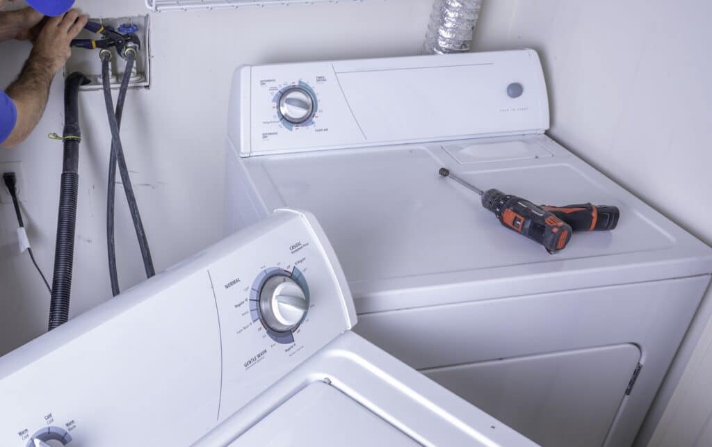 Plumber installing appliance water hookups.
