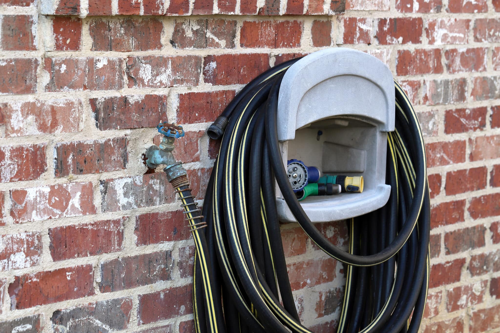 Water faucet and hose on side of brick house, hose bib replacement in Oakley, OH.